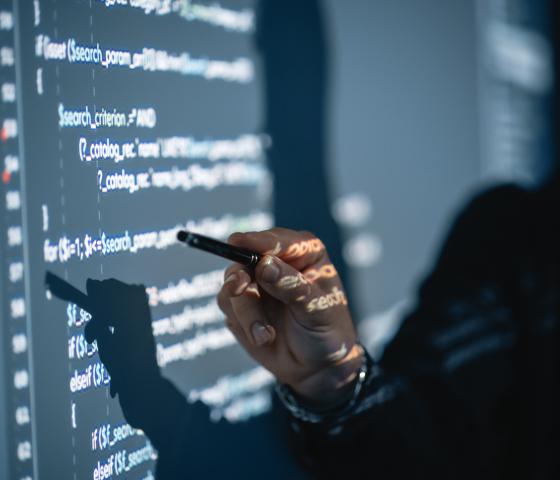 Pointing at a whiteboard with code on it