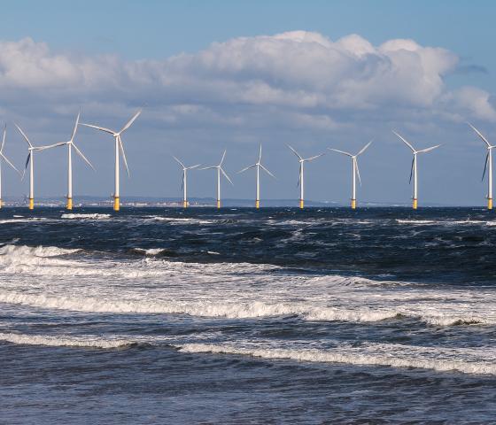 Lines of offshore wind turbines in the rolling surf off the North Sea coast