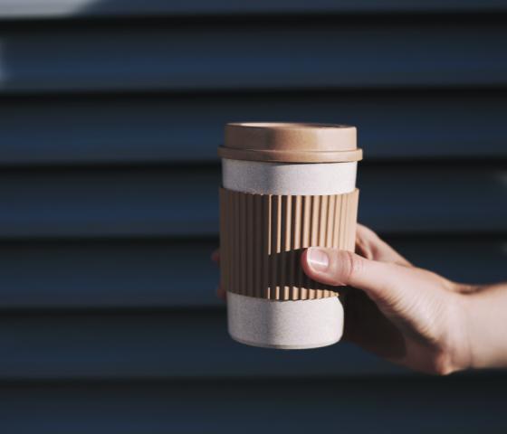 one hand holding a sustainable paper coffee mug