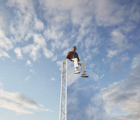 Man sitting on a ladder surrounded by blue sky